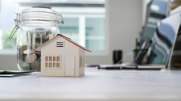 Home,Model,And,Glass,Jars,With,Coins,Putting,On,White